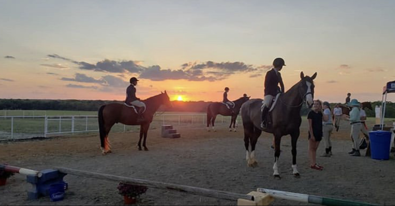 Photo of riders at a horse show at sunset